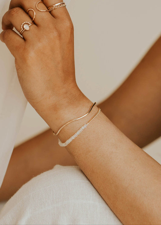 Close-up of a person's arm with jewelry against a neutral background