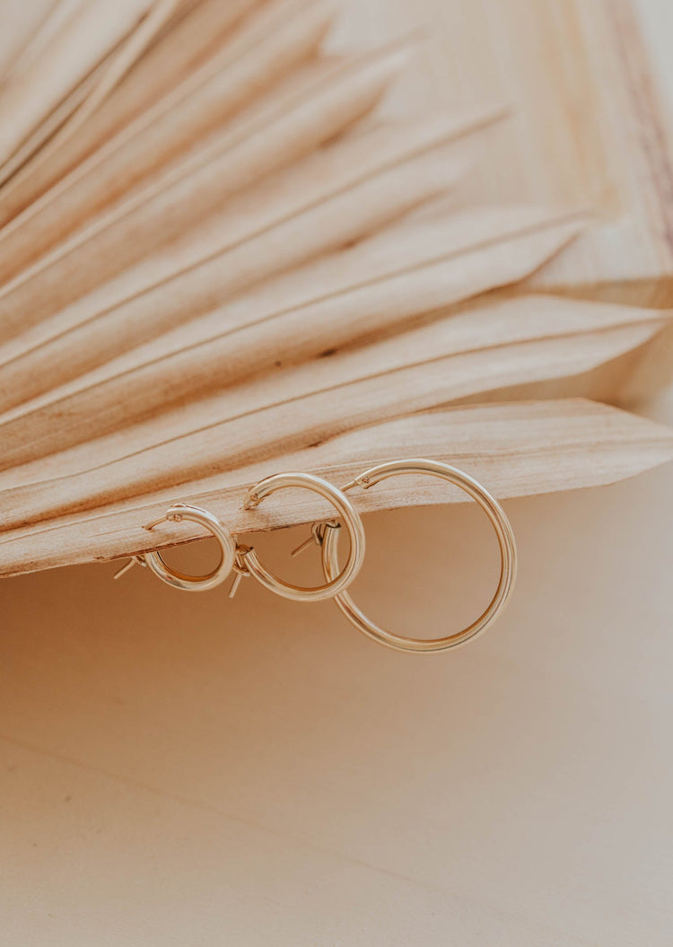 Thick gold hoops styled in an ear with small gold hoop earring and twist earrings by Hello Adorn in 14k gold fill.