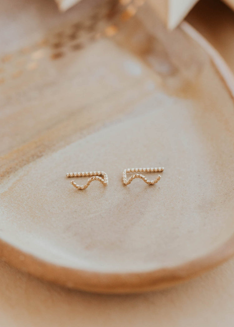 Gold earrings on a beige plate