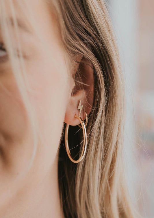 Large gold hoop earring styled with lightning bolt earrings and a small gold hoop earring by Hello Adorn.