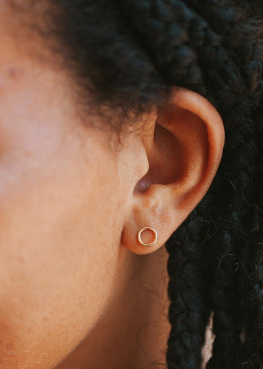 A pair of open circle earrings for everyday wear shown on a model in a stud earring style by Hello Adorn in 14k gold fill.