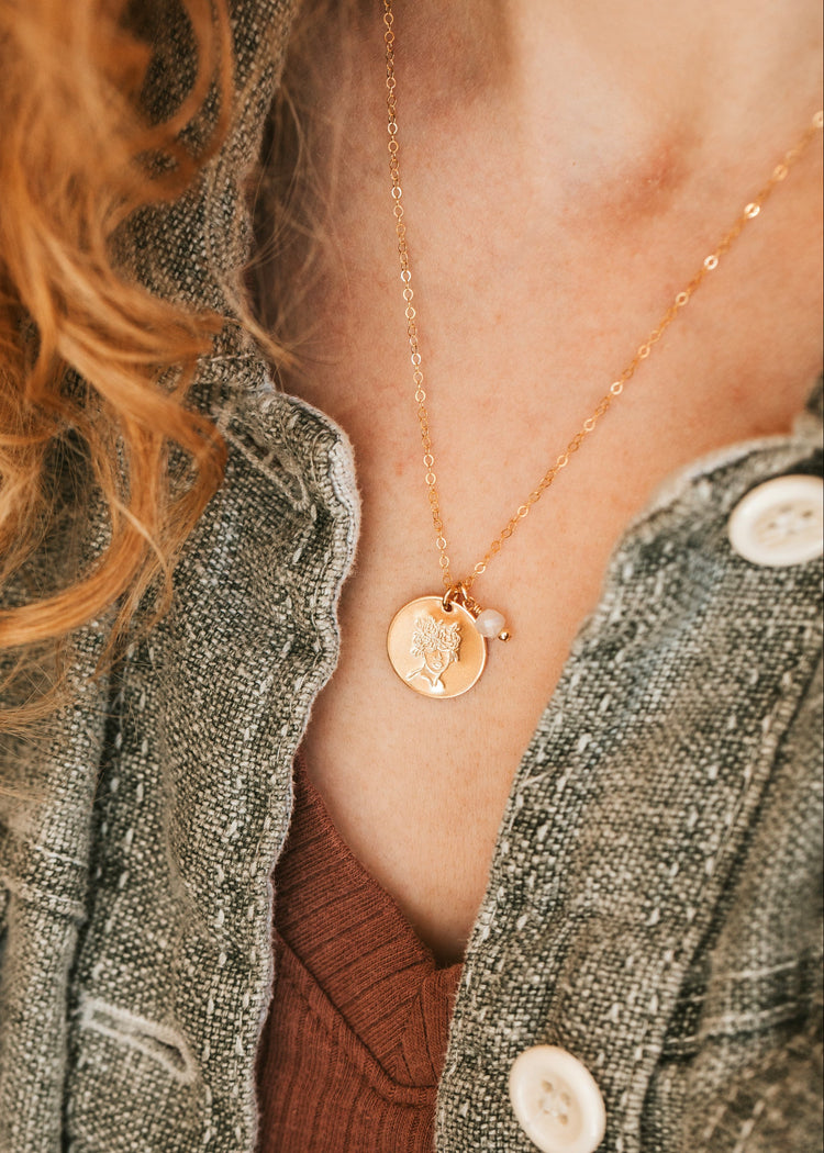 Person wearing a gold Hello Adorn Mental Health necklace with circular pendants and meaning charms