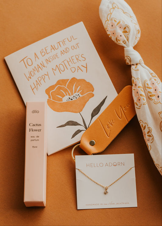 Gift set with perfume, necklace, and card on a brown background