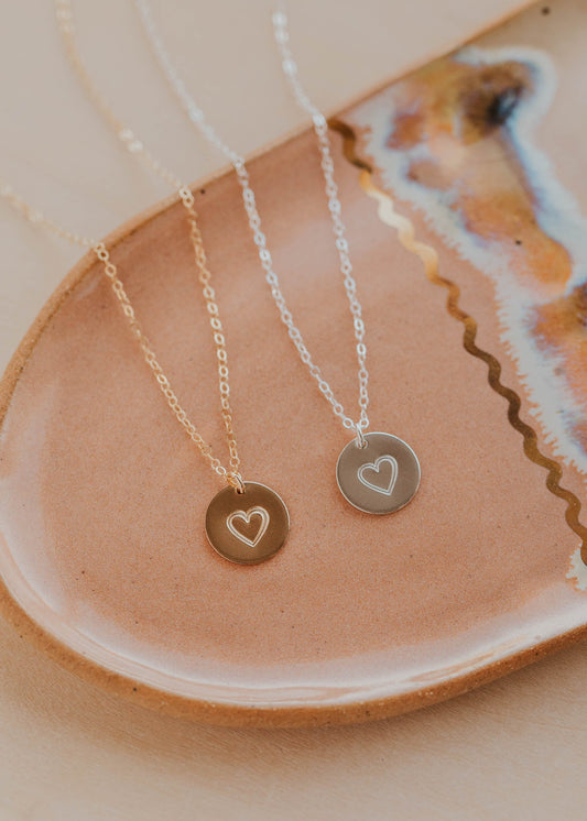 Three necklaces with heart pendants on a ceramic dish.