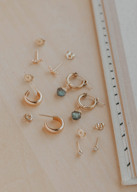 Collection of gold earrings on a light surface with a ruler for scale.