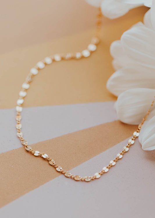 Pearl and gold chain necklace on a striped background with flowers