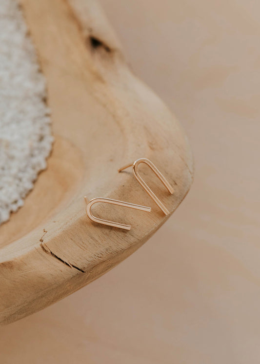 Gold paper clip on a wooden surface with a blurred background