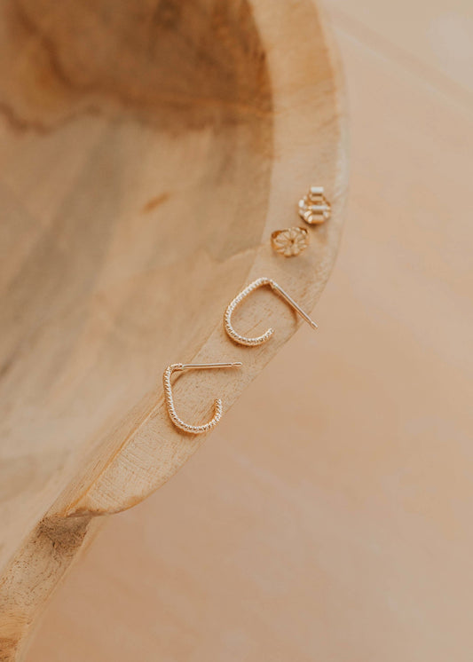 Gold earrings on a wooden surface