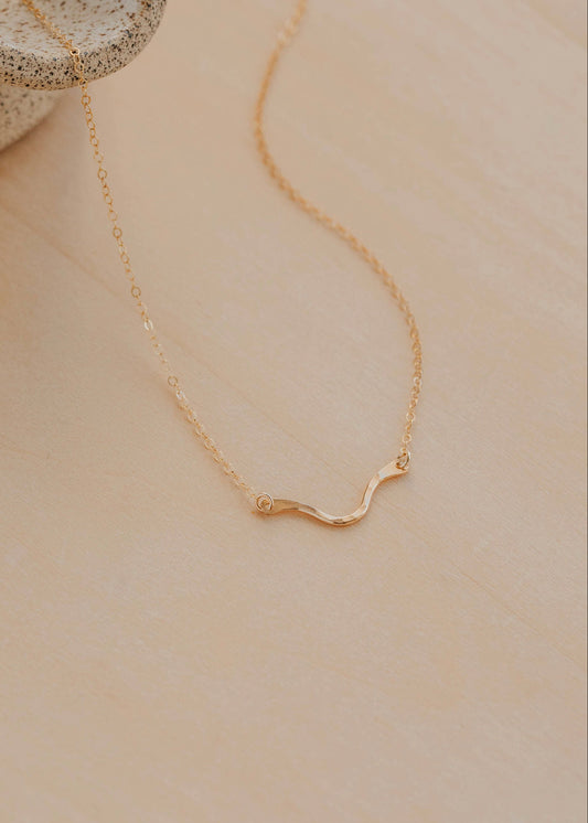 Gold necklace on a beige surface