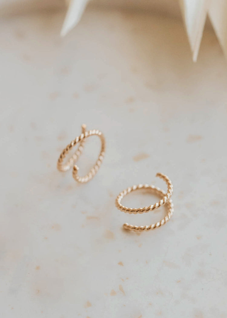 14k gold fill tiny twist earrings by Hello Adorn on a cream surface with white star decoration