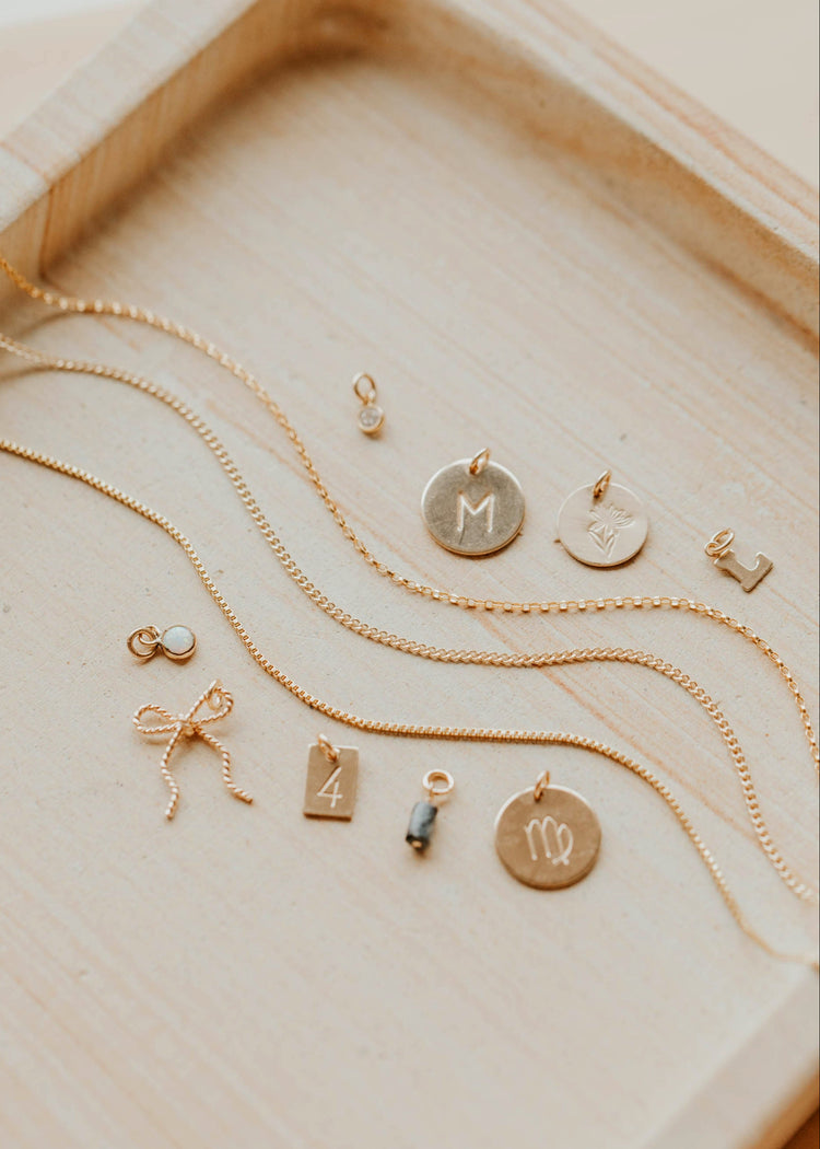 Gold necklaces with various pendants on a wooden surface