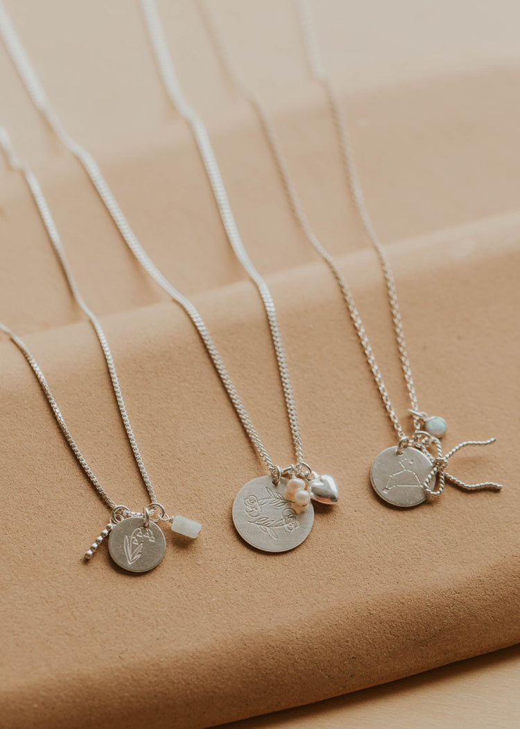 Silver necklaces with various pendants on a beige background