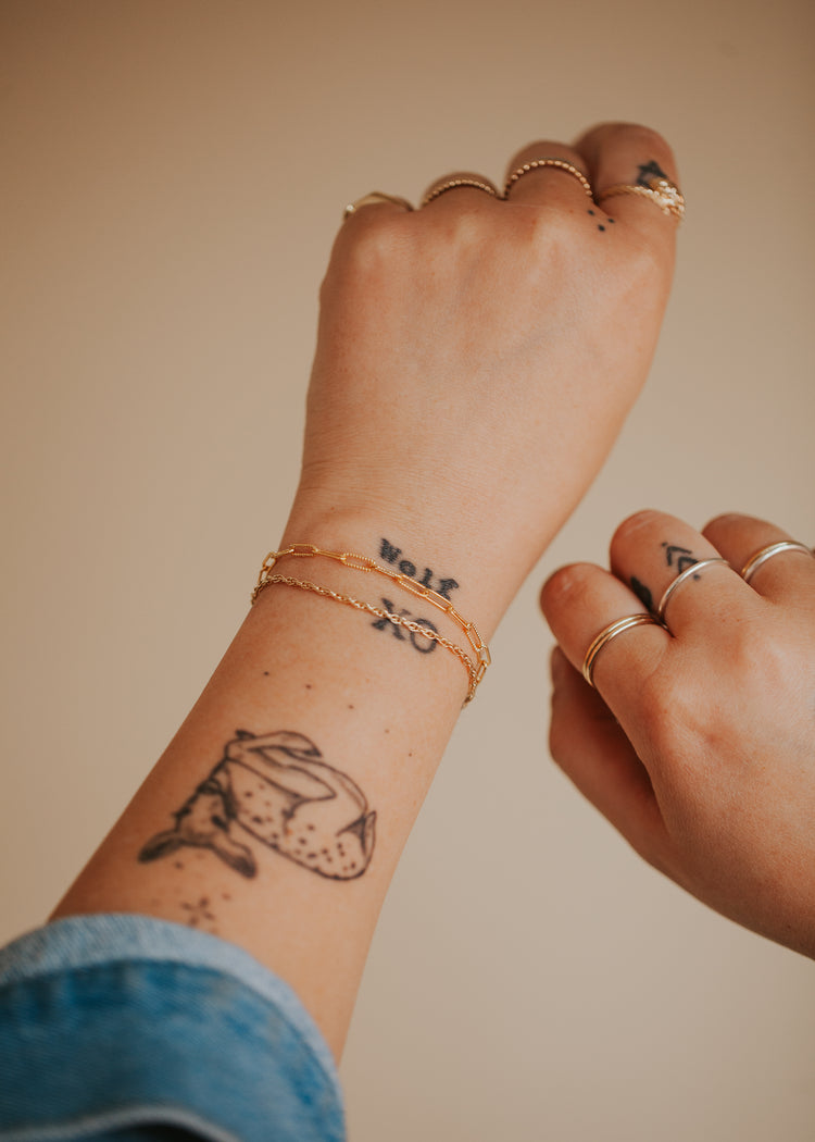 A model styling two 14kt Gold Fill bracelets featuring a double rope chain bracelet with minimal link chain bracelet.