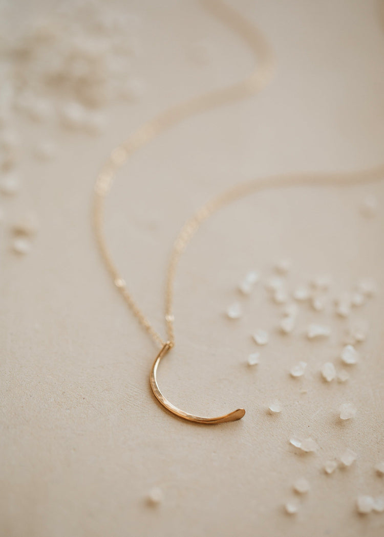 A crescent moon pendant attached to a dainty chain necklace created by Hello Adorn, this mini-moon necklace is perfect to finish a necklace layering look.