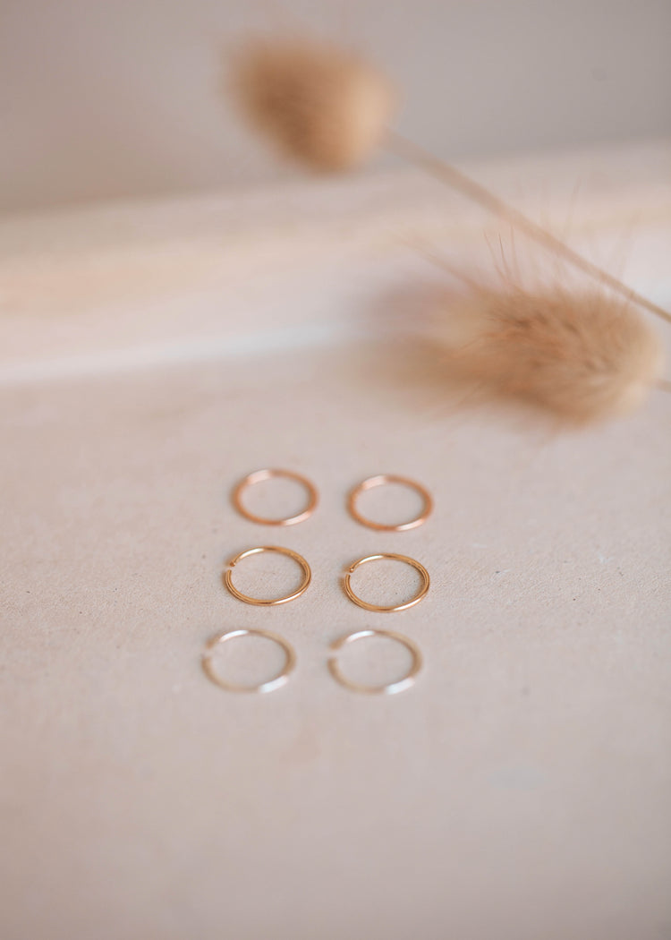 Tiny hoop earring by Hello Adorn shown laying flat in three colors of sterling silver hoop earring, rose gold hoop earring, and 14k gold fill hoop earring.
