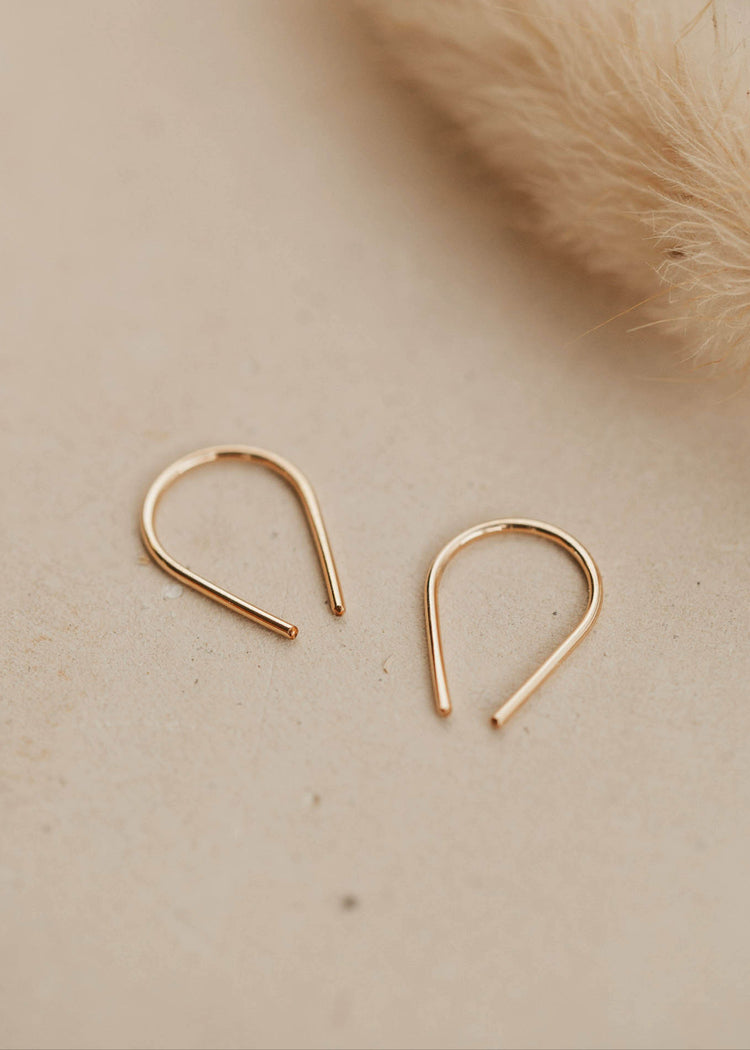 14k gold fill tiny horseshoe threader earrings by Hello Adorn on a beige surface with pampas grass