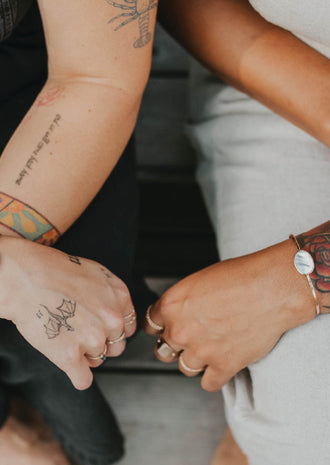 two arms feature cuff bracelets, one with a dark stone and one with a light stone