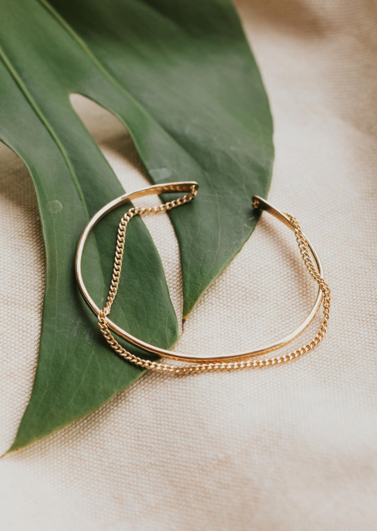 The Tides Cuff from Hello Adorn shown as a gold cuff bracelet with a chain bracelet attached to create a 2 in 1 bracelet.