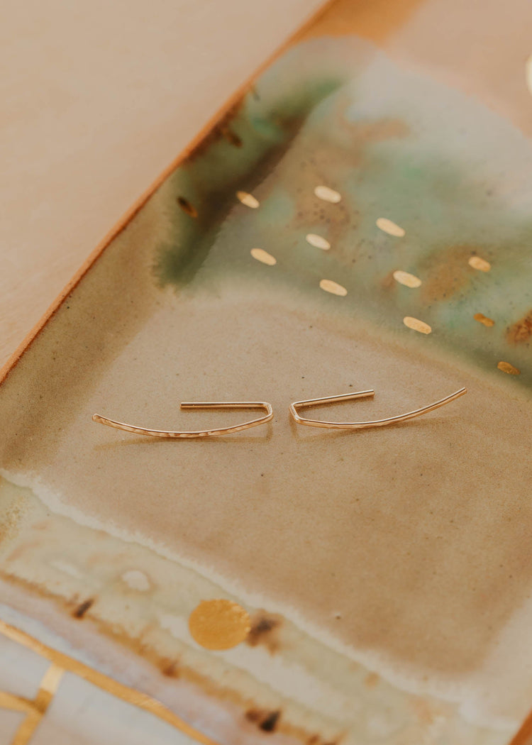 Gold earrings on a textured ceramic surface