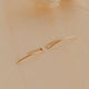 Two gold earrings on a beige background
