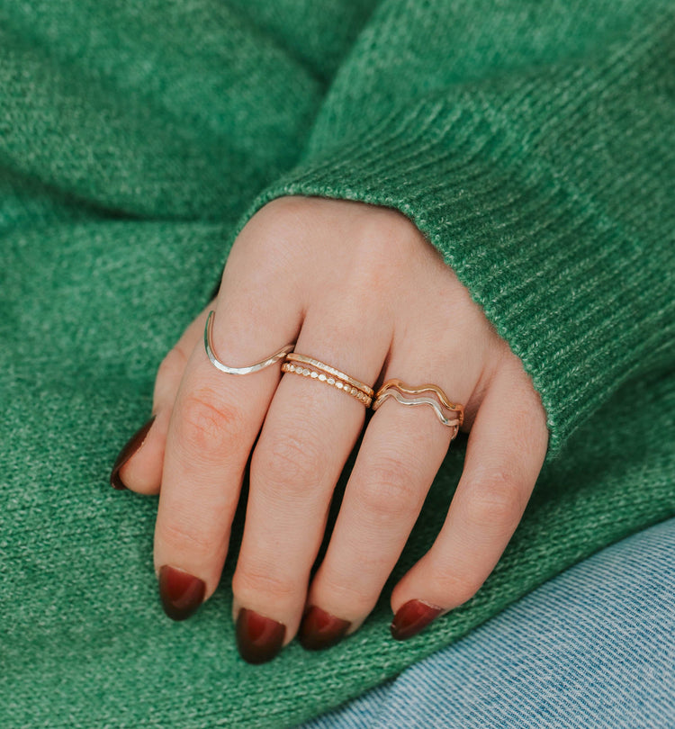 Hand with gold rings on a green fabric background