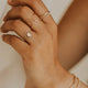 Close-up of a hand wearing gold rings and a bracelet on a blurred background