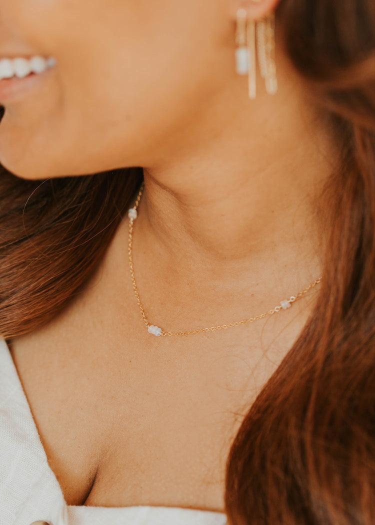 Close-up of a woman wearing gold earrings and a necklace with a blurred background