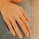 Close-up of hands wearing multiple gold rings on a neutral background