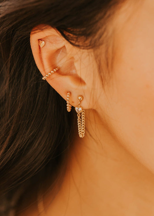Close-up of a person wearing gold earrings with a blurred background