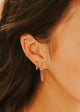 Close-up of a person wearing gold earrings with a blurred background