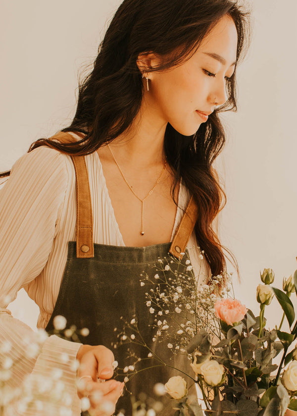 Woman arranging flowers in a vase with a neutral background