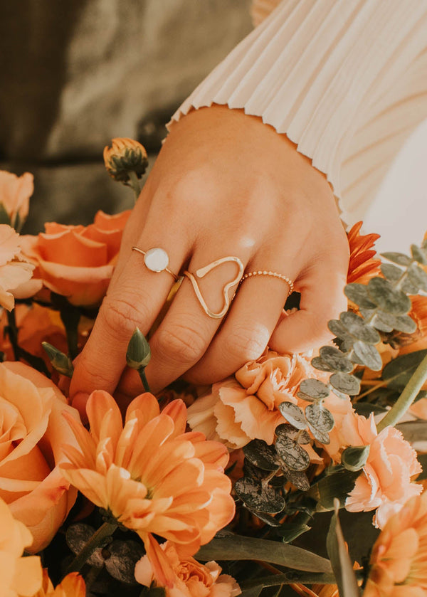 Person arranging a bouquet of orange flowers with greenery.