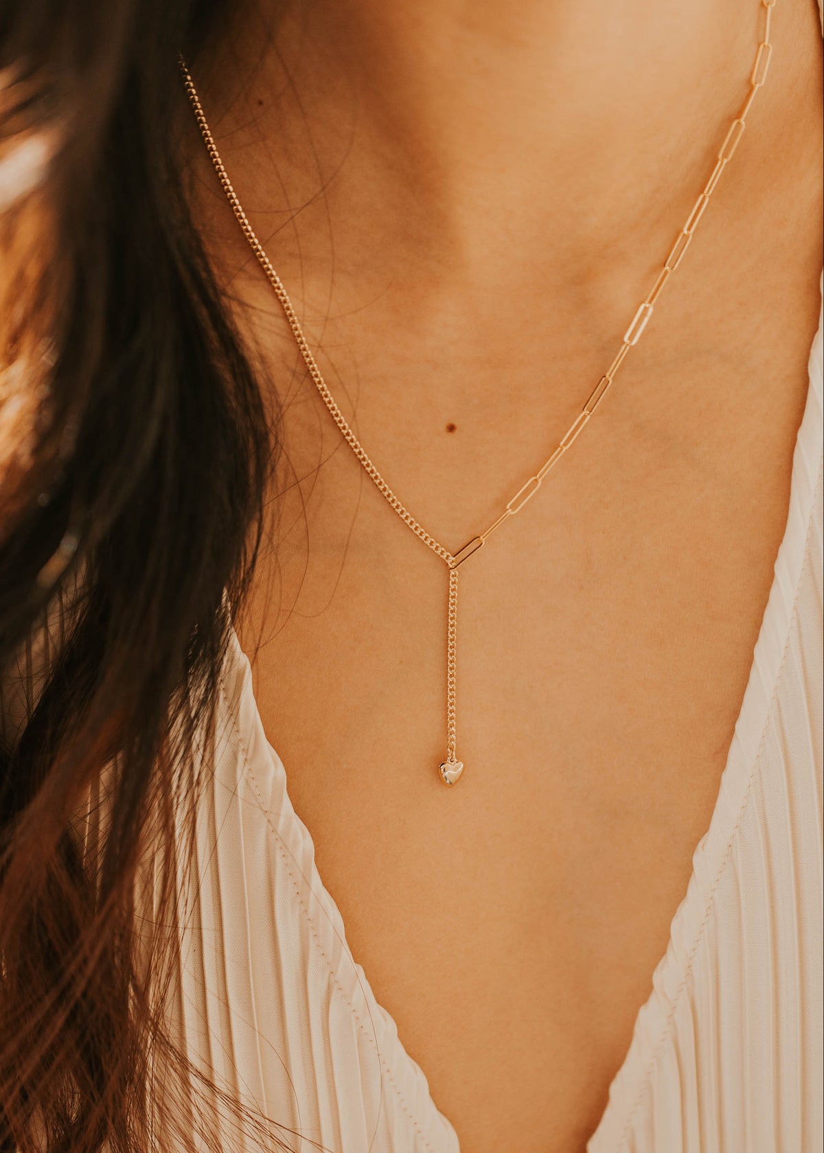 Gold necklace worn by a person with a blurred background