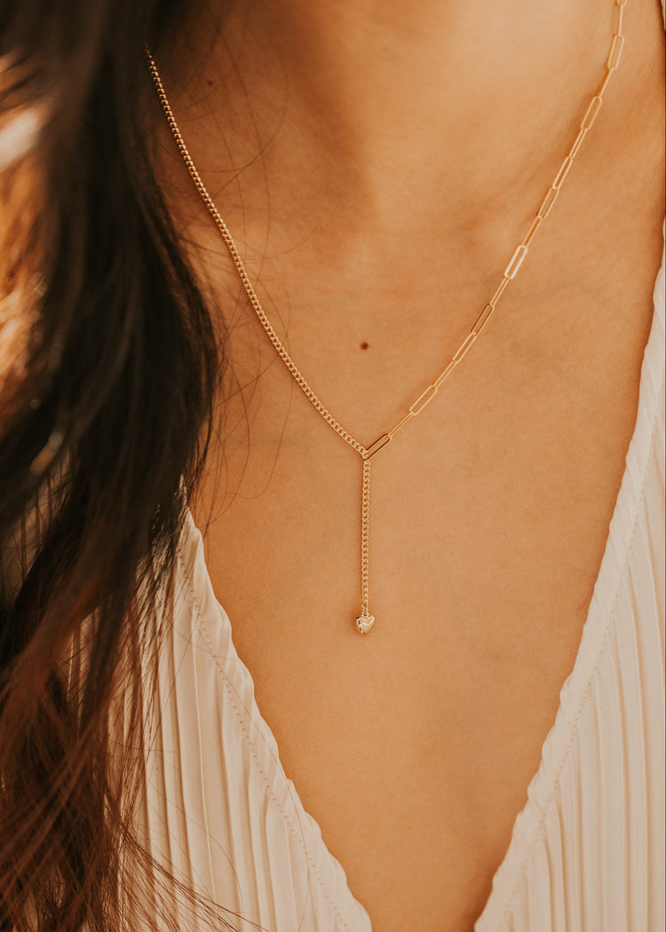 Gold necklace worn by a person with a blurred background