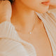 Close-up of a person wearing a delicate necklace with a small pendant.