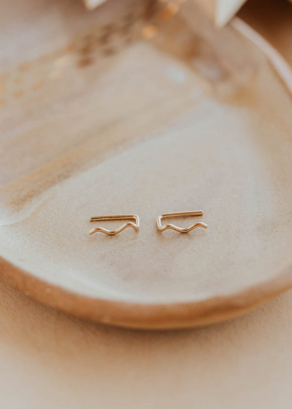 Gold earrings on a beige dish with a neutral background