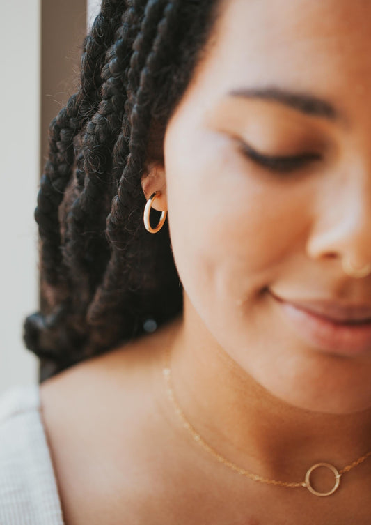 Medium gold hoop earring in 14k gold fill styled with a circle necklace by Hello Adorn.