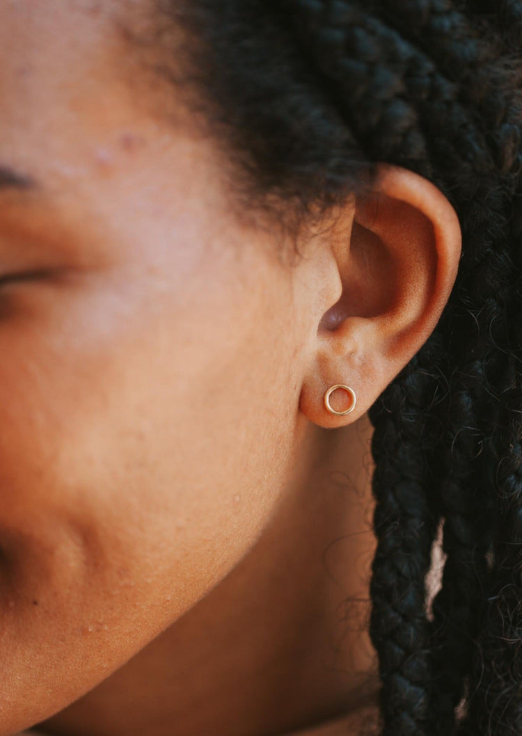 A pair of open circle earrings for everyday wear shown on a model in a stud earring style by Hello Adorn in 14k gold fill.