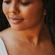 A model wearing a gold circle necklace from Hello Adorn in the Full Circle Necklace design, handmade jewelry using a circle pendant and gold chain necklace.