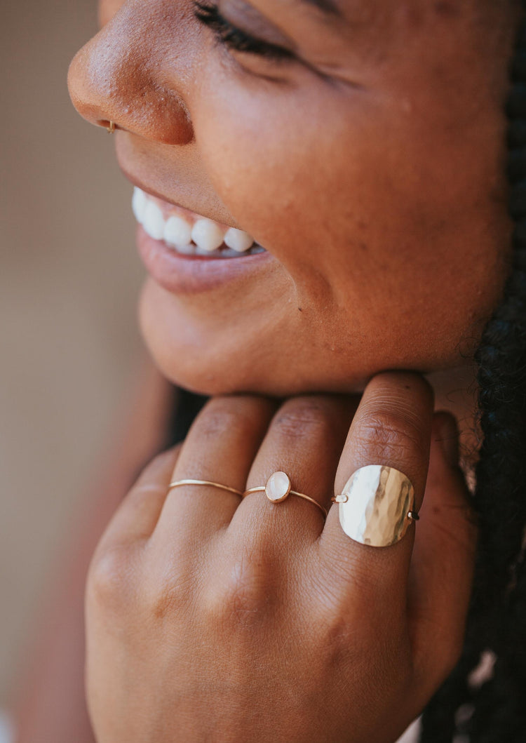 A gold ring stack with a 3 ring stack using a thin gold ring, a gemstone ring with a Rose Quartz stone, and the Supermoon Ring which is a hammered ring created to look like a moon ring by Hello Adorn.