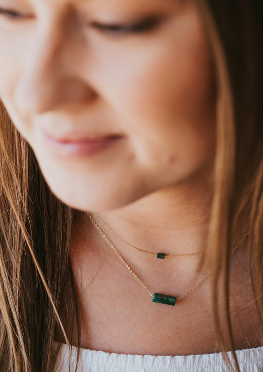 A young woman wearing 14kt Gold Fill necklaces with a jade green gemstone.