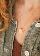 Person wearing a gold Hello Adorn Mental Health necklace with circular pendants and meaning charms