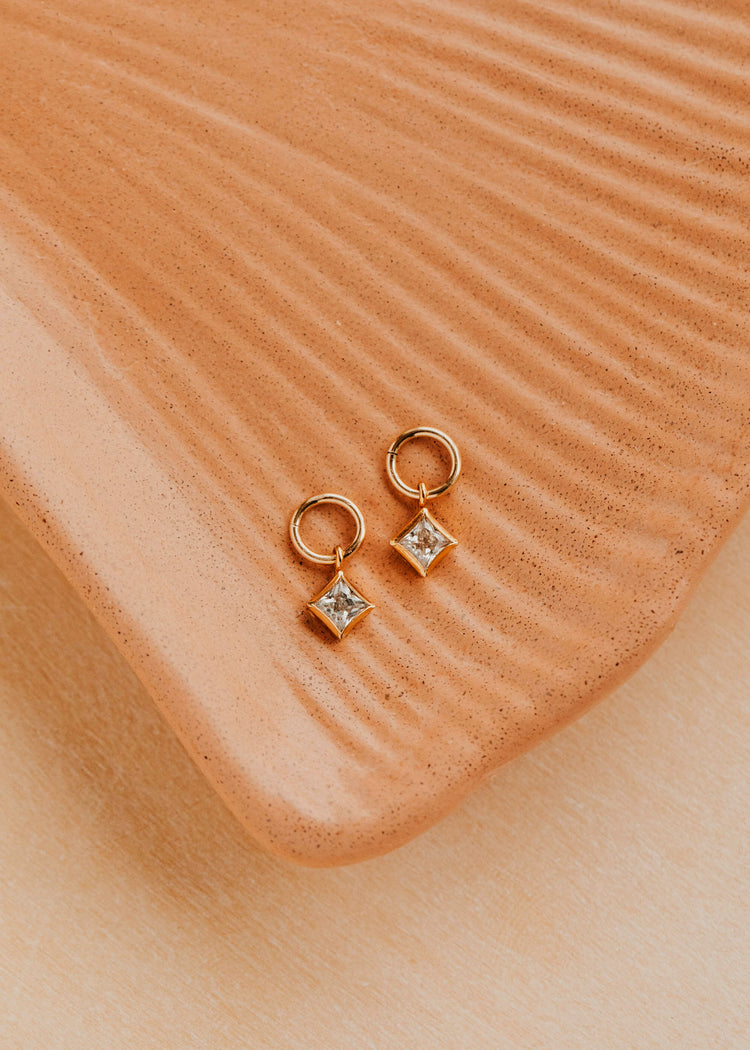 14K Gold Fill Grace Charms by Hello Adorn - pair of CZ star charms on gold huggies on ceramic dish