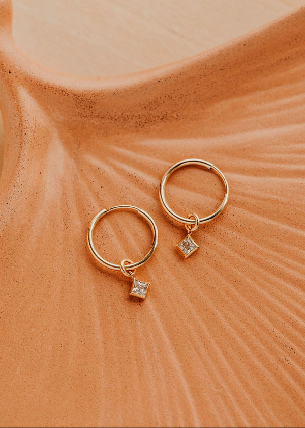 14K Gold Fill Grace Hoops by Hello Adorn - pair of gold huggies with CZ star charms on ceramic dish