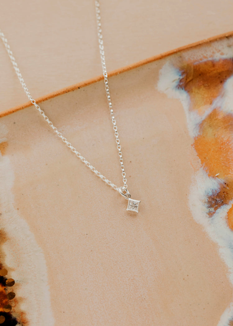 Sterling Silver Grace Necklace by Hello Adorn - tiny CZ pendant on silver chain against ceramic dish