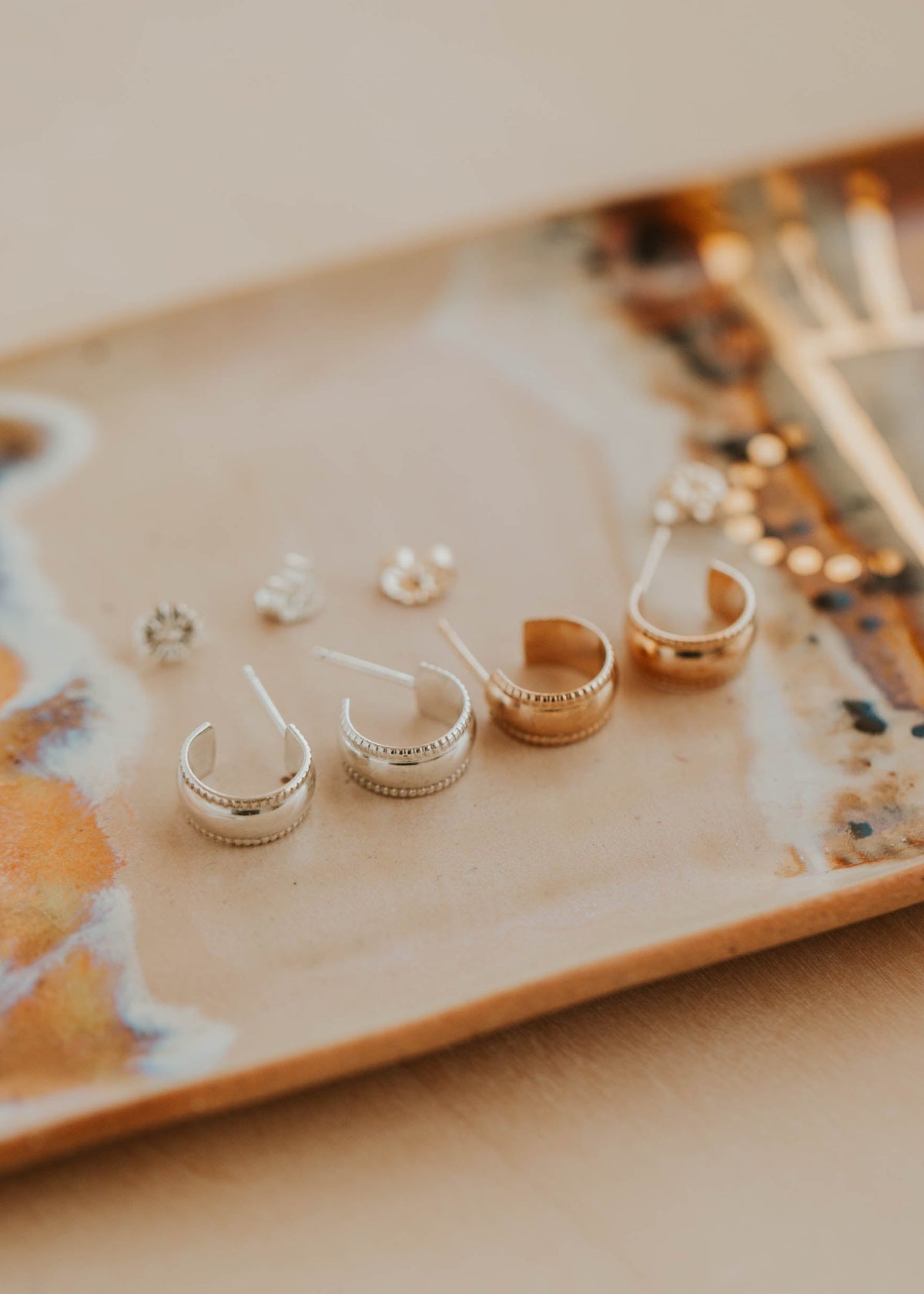 Collection of gold earrings on a decorative plate with a blurred background