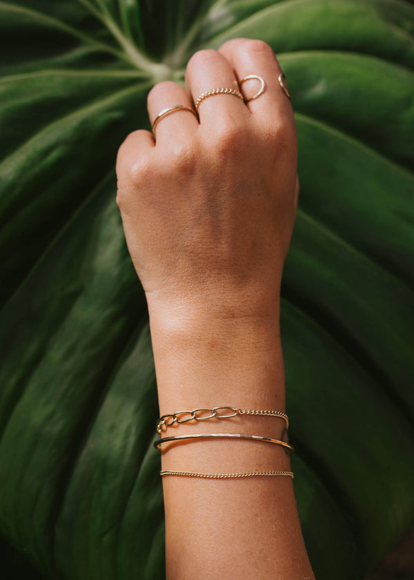A jewelry style created by Hello Adorn featuring a ring stack and a bracelet stack. The bracelet stack features a cuff bracelet and a chain bracelet. The ring stack features an open ring, a chain ring, and a ring band.