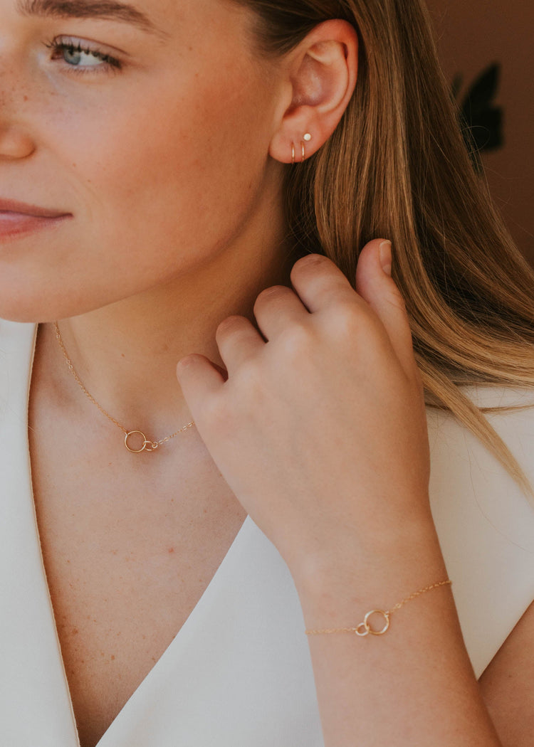 Woman wearing gold earrings and bracelet, close-up of face and hand