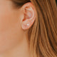 Close-up of an ear with a silver earring and blonde hair.
