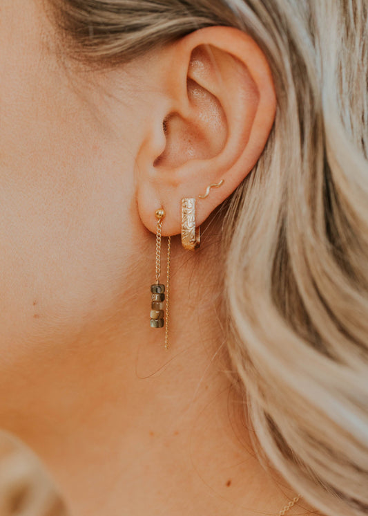Close-up of an ear with gold earrings and a blurred background